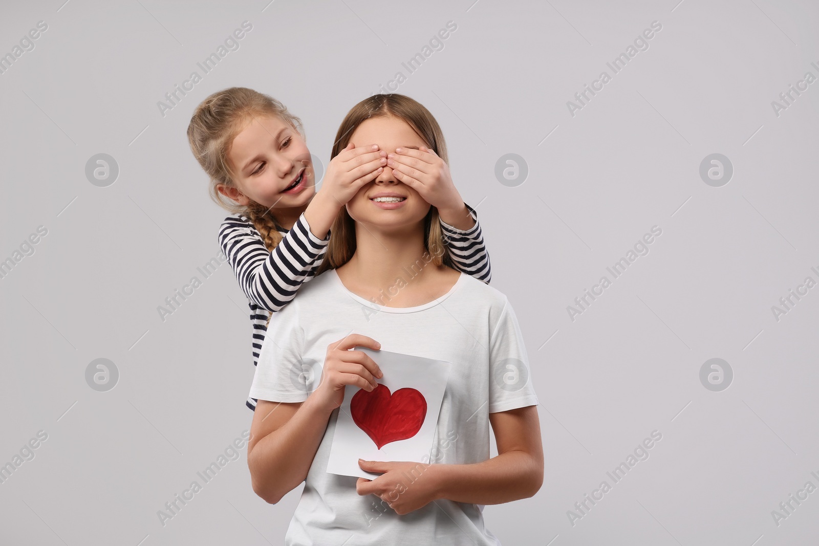 Photo of Little daughter congratulating her mom with postcard on white background, space for text. Happy Mother's Day