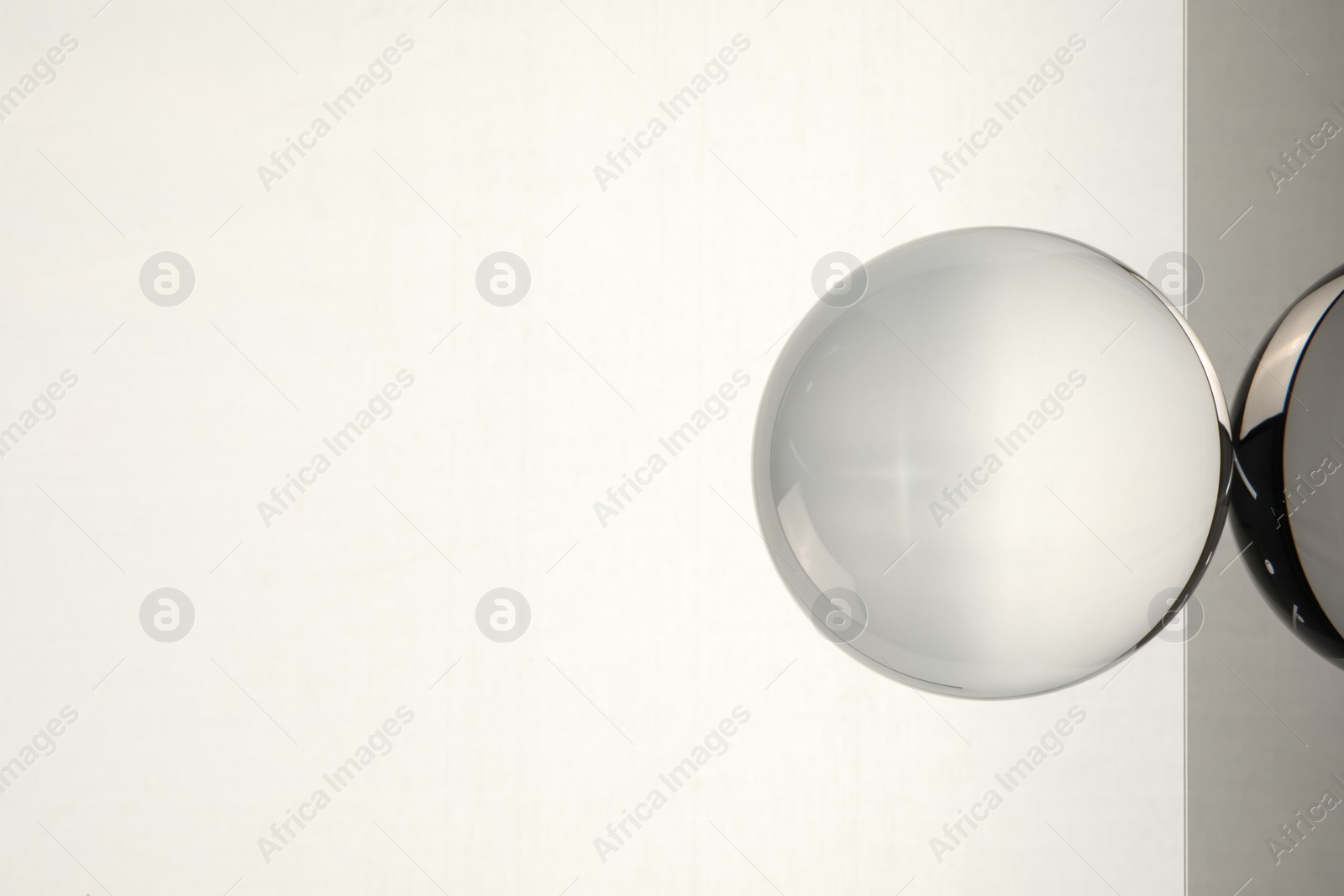 Photo of Transparent glass ball on light grey background. Space for text