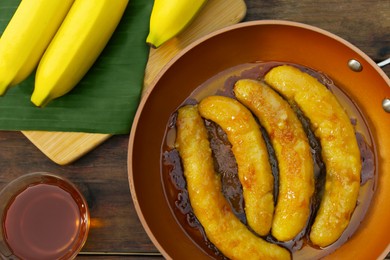 Delicious fresh and fried bananas with rum on wooden table, flat lay
