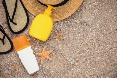 Photo of Flat lay composition with bottles of sun protection body cream on sand beach, space for text