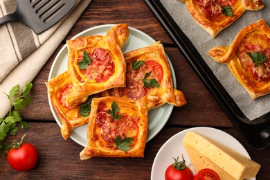 Photo of Fresh delicious puff pastry with cheese, tomatoes and parsley on wooden table, flat lay