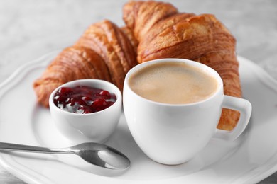 Tasty breakfast. Cup of coffee, fresh croissants and jam on table, closeup