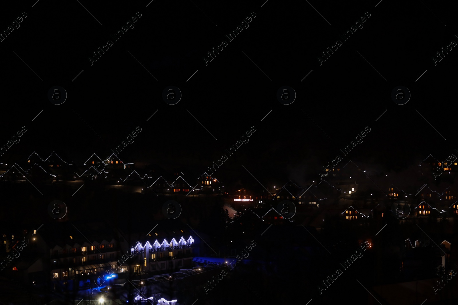 Photo of Night landscape with mountain village near forest in winter