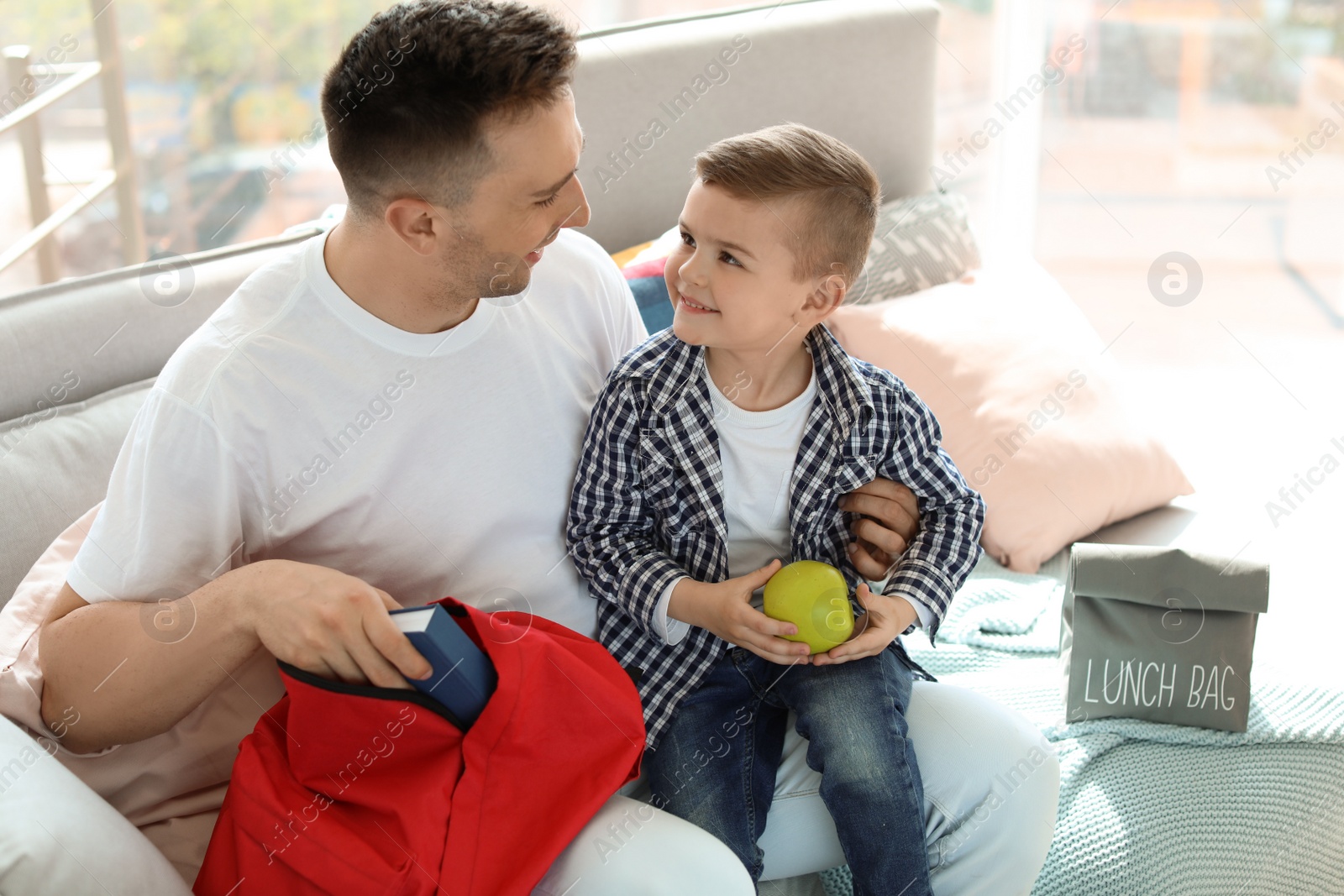 Photo of Young man helping his little child get ready for school at home