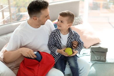 Young man helping his little child get ready for school at home