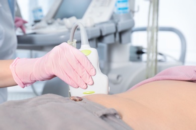 Photo of Doctor conducting ultrasound examination of patient's abdomen in clinic, closeup