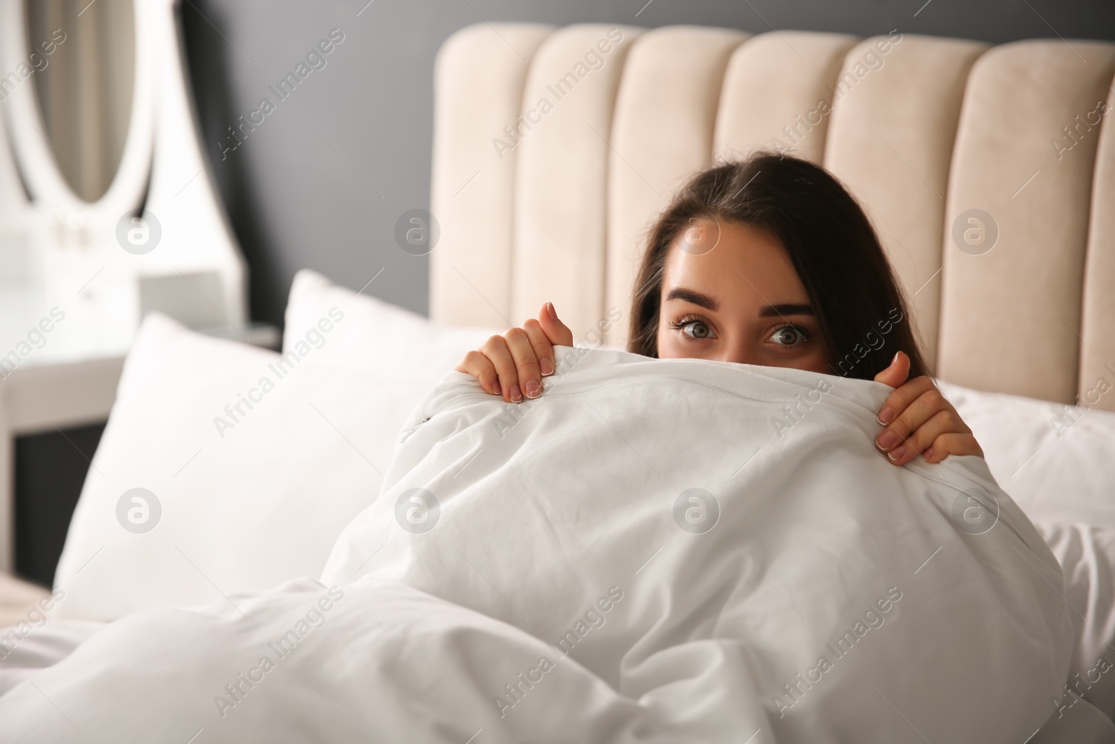 Photo of Beautiful young woman wrapped with soft blanket relaxing on bed at home