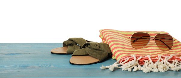 Photo of Beach towel, slippers and sunglasses on light blue wooden surface against white background. Space for text