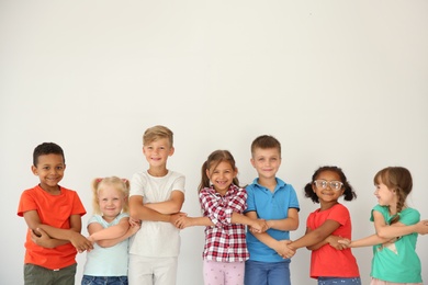 Photo of Little children holding hands on light background. Unity concept