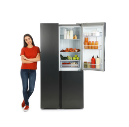 Young woman near open refrigerator on white background