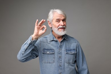 Senior man with mustache on grey background