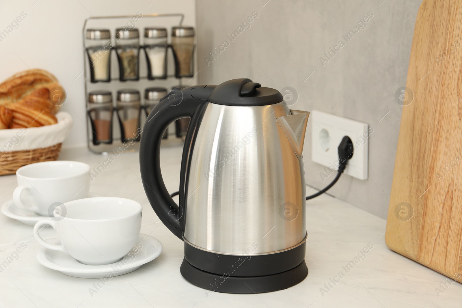 Photo of Electric kettle and cups on counter in kitchen