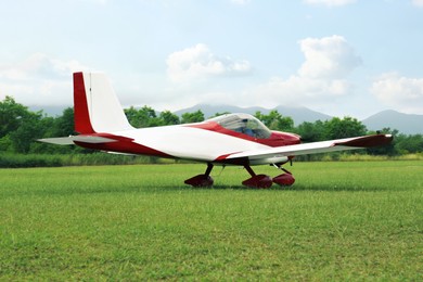 Photo of Ultralight aircraft on green grass near trees