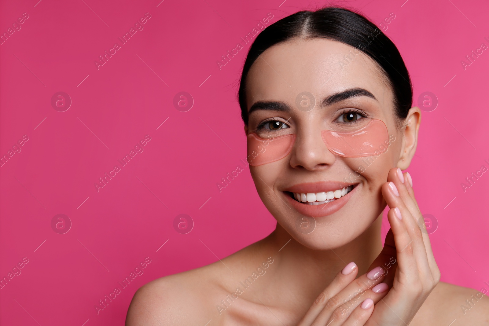 Photo of Beautiful young woman with under eye patches on pink background, space for text