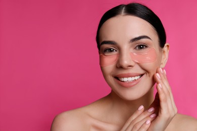 Beautiful young woman with under eye patches on pink background, space for text