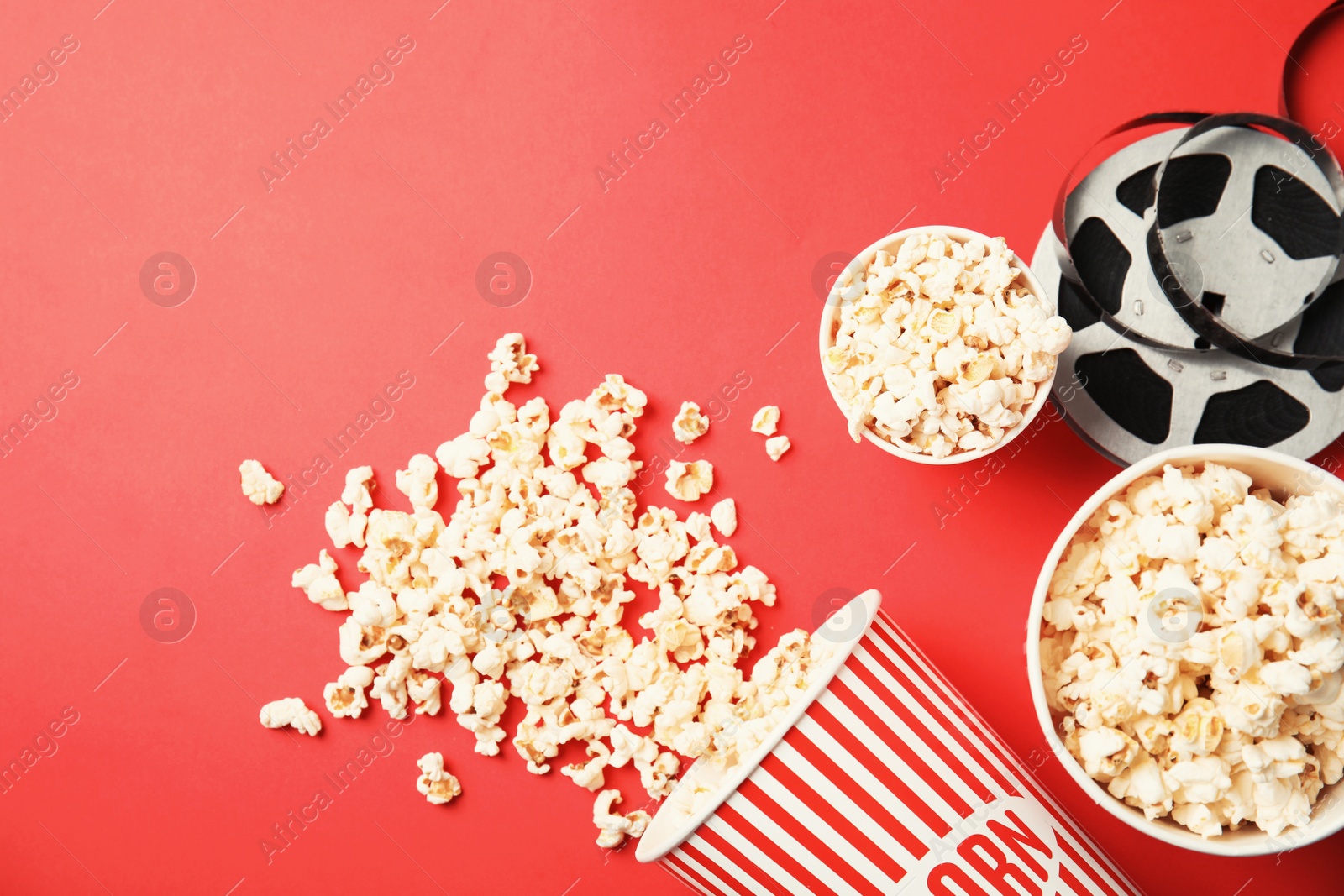 Photo of Tasty popcorn and film reel on color background, top view with space for text. Cinema snack