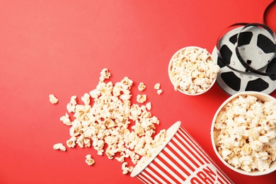 Tasty popcorn and film reel on color background, top view with space for text. Cinema snack