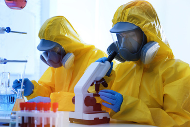 Scientists in chemical protective suits working at laboratory. Virus research