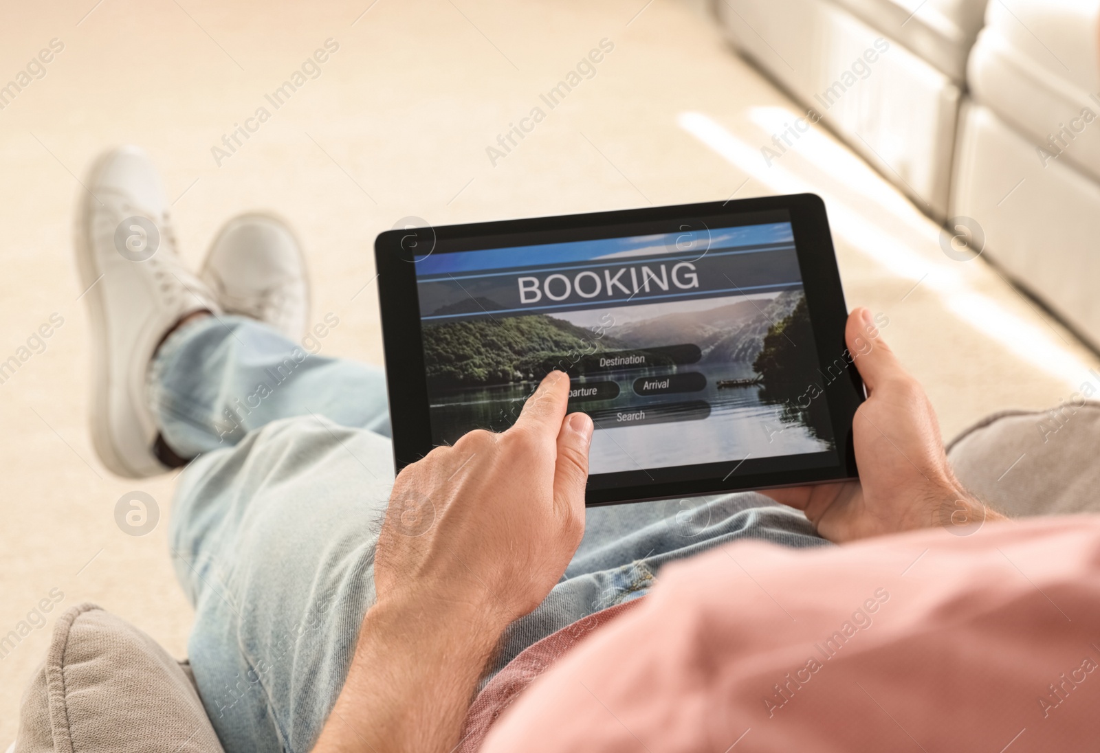 Photo of Man booking tickets online on sofa indoors, closeup. Travel agency concept