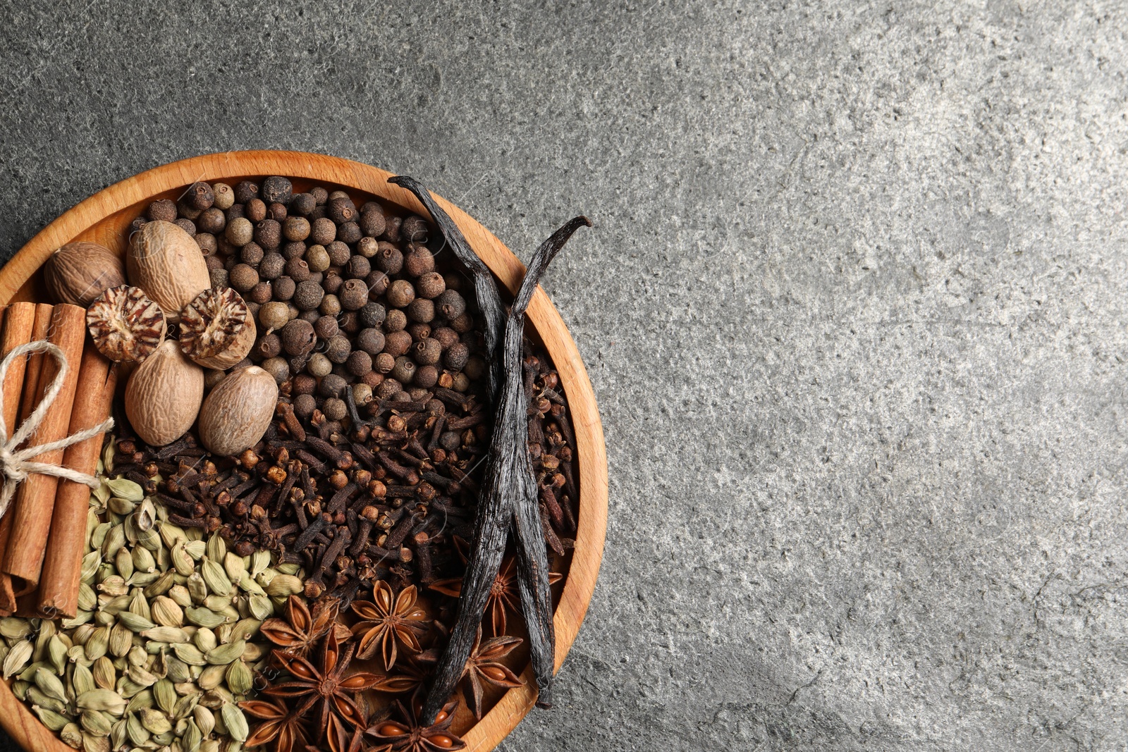 Photo of Different spices and nuts on gray textured table, top view. Space for text