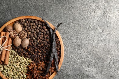 Different spices and nuts on gray textured table, top view. Space for text