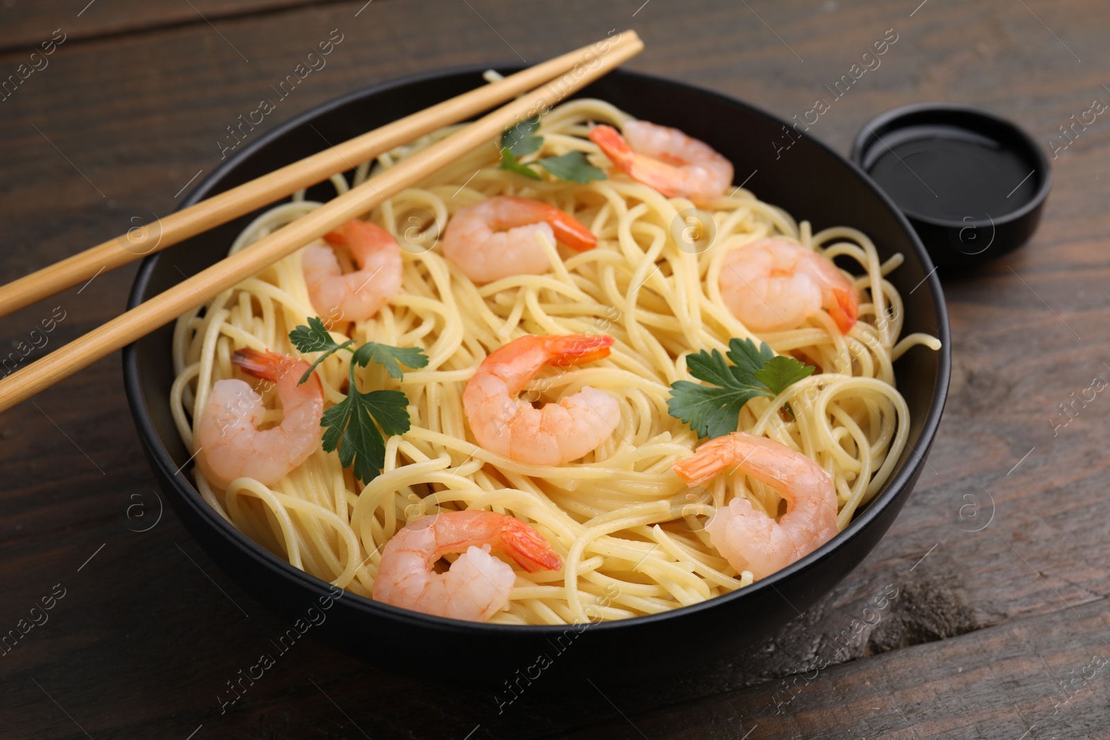 Photo of Tasty spaghetti with shrimps, parsley and soy sauce on wooden table, closeup