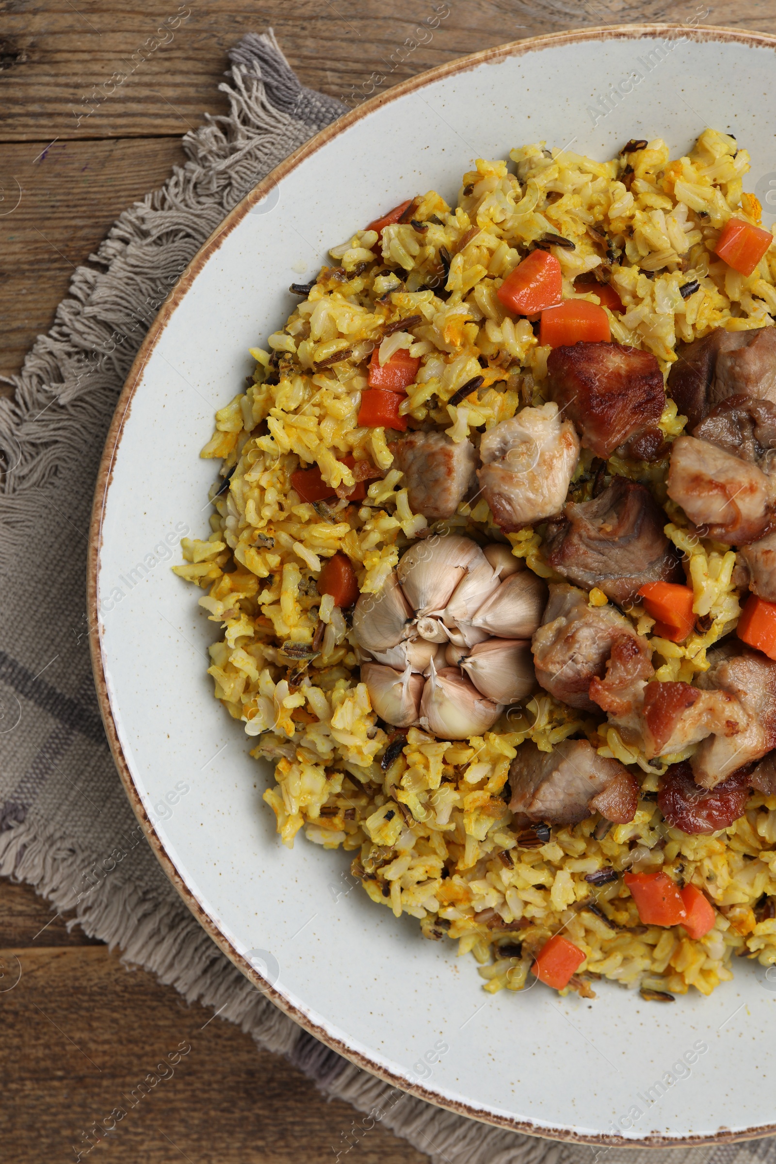 Photo of Delicious pilaf on wooden table, top view