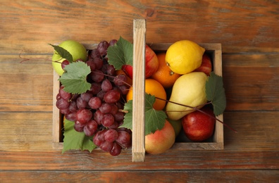 Photo of Crate with different fruits on wooden table, top view