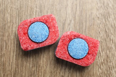 Photo of Two dishwasher detergent tablets on wooden table, flat lay