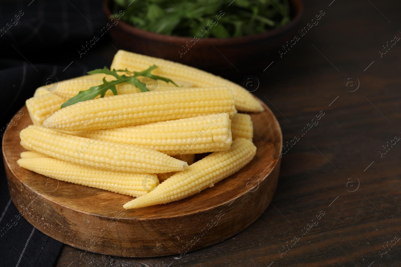 Photo of Tasty fresh yellow baby corns on wooden table, space for text