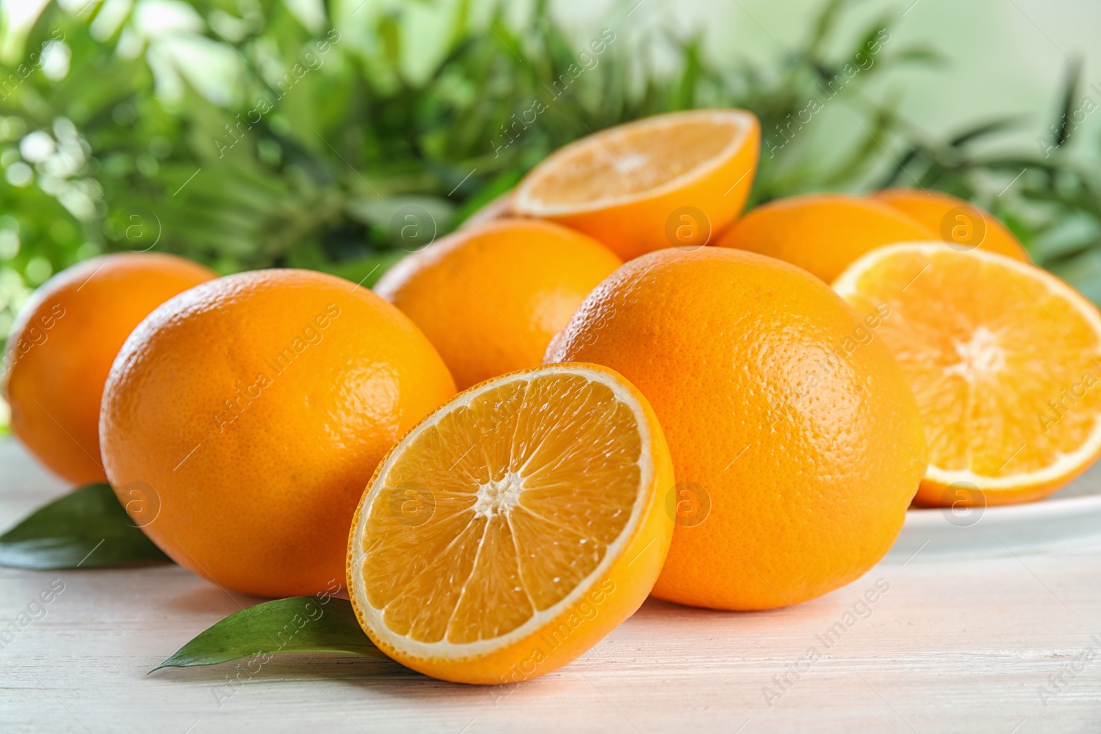 Photo of Fresh juicy oranges with leaves on wooden table