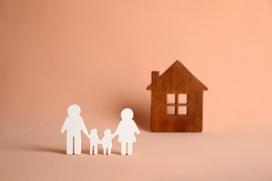 Photo of Figures of family and house on pink background