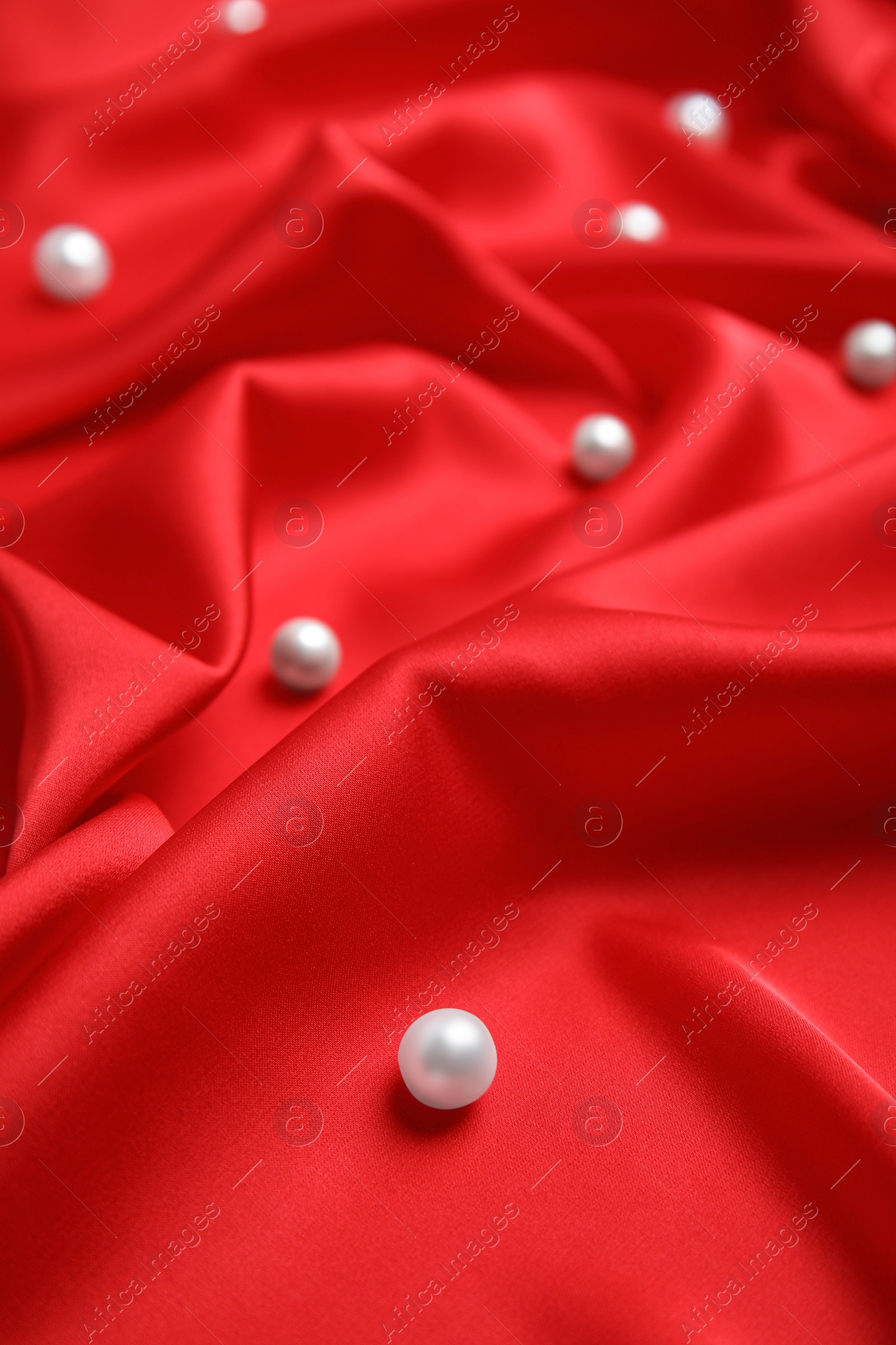 Photo of Many beautiful pearls on delicate red silk