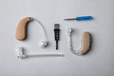 Photo of Flat lay composition with hearing aids and accessories on grey background
