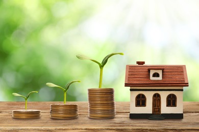 Image of Real estate investing. House model and coins on wooden table