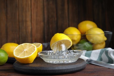 Photo of Glass squeezer and fresh lemons on wooden table