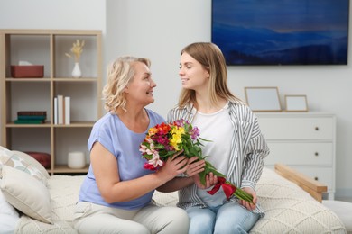 Young daughter congratulating her mom with flowers at home. Happy Mother's Day