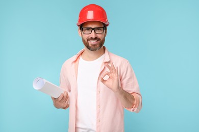 Photo of Architect in hard hat with draft showing OK gesture on light blue background