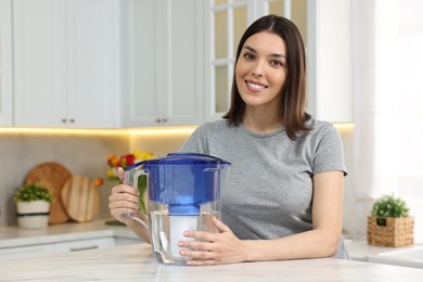 Woman with filter jug of water in kitchen