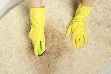Photo of Woman removing stain from beige carpet, top view