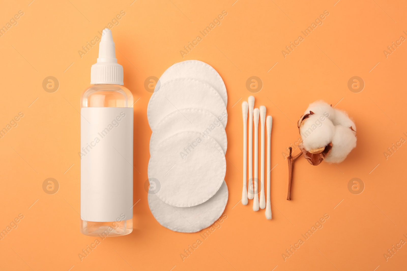 Photo of Flat lay composition with makeup remover and cotton flower on pale orange background