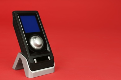 Photo of Modern remote for audio speakers on red background, closeup. Space for text