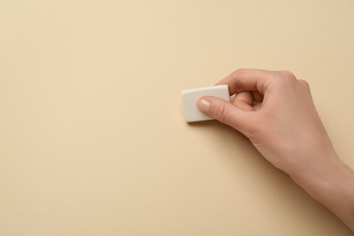 Photo of Woman erasing something on beige background, closeup. Space for text