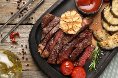 Delicious grilled beef steak with vegetables and spices on wooden table, flat lay