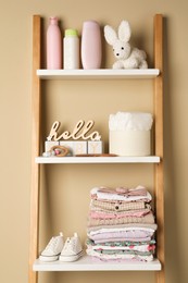 Photo of Baby clothes, toy and accessories on wooden rack