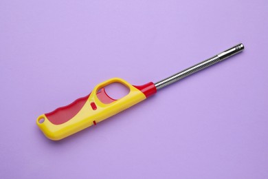 Photo of One gas lighter on violet background, top view