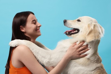 Photo of Happy woman with cute Labrador Retriever dog on light blue background. Adorable pet