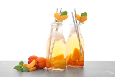 Photo of Delicious refreshing drink with apricot on light grey table against white background