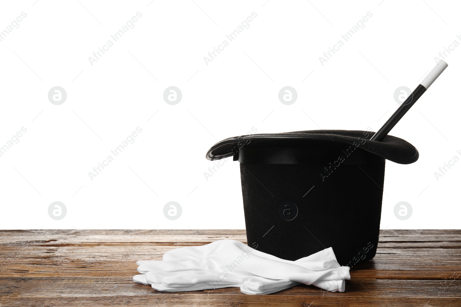 Photo of Magician's hat, gloves and wand on wooden table against white background