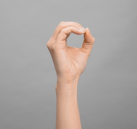 Photo of Woman showing O letter on grey background, closeup. Sign language
